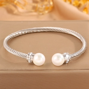 Détail d'un bracelet torsadé argenté avec perles blanches et pierres de zircone brillantes