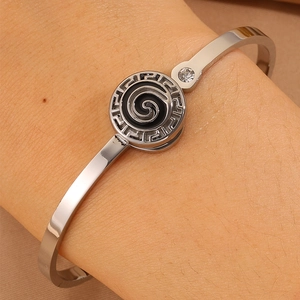 Detail of silver stainless steel cuff bangle with Greek Key pattern and black vortex inlay