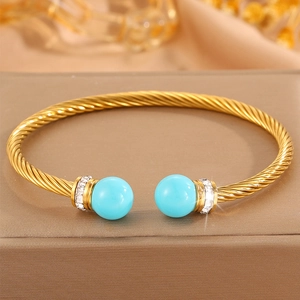 Vue détaillée d'un bracelet doré torsadé orné de perles turquoise et de zircons blancs
