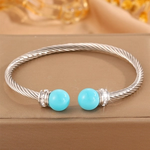 Détail macro du bracelet câble torsadé argenté avec perle bleue et strass brillants