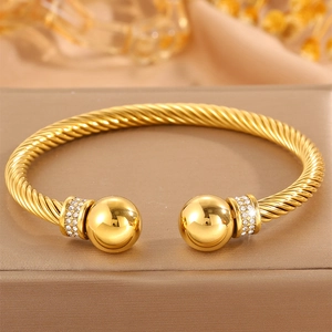Détail de bracelet torsadé doré avec extrémités sphériques serties de cristaux