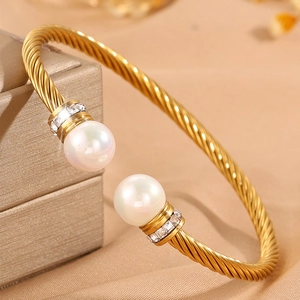 Détail d'un bracelet torsadé doré orné de perles blanches et de brillants élégants