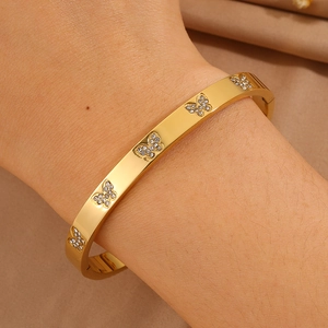 Detail van een gouden vlinderarmband met sprankelende stenen en een zijwaartse sluiting