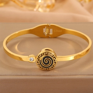 Detailed close-up of golden stainless steel cuff with black enamel Greek key and zircon