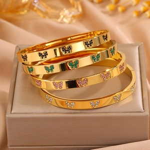 Detailopname van vier gouden vlinderarmbanden met kleurrijke strassteentjes