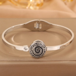 Detailed close-up of stainless steel bangle with Greek key pattern and small crystal