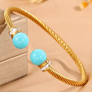 Détail d'un bracelet torsadé doré avec perles turquoise et accents en zircone pavé