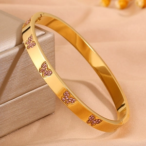 Macro-opname van gouden vlinderarmband met roze zirkonia op zijden achtergrond
