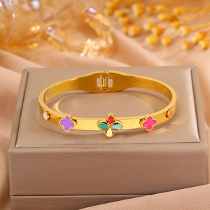 Détail du bracelet trèfle doré avec fleurs en émail coloré sur un coffret en soie