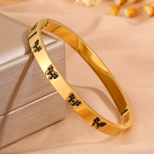 Detail van gouden vlinderarmband met zwarte kristallen op een satijnen ondergrond