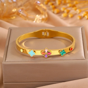 Détail d'un bracelet trèfle doré avec breloques en émail coloré et fermoir à charnière