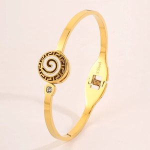 Detailed view of gold stainless steel bangle with Greek meander and white enamel motif