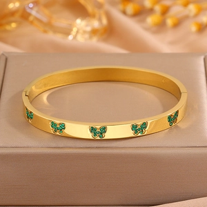Gedetailleerd beeld van een gouden vlinderarmband met groene fonkelende kristallen