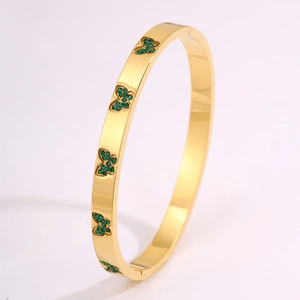 Detailopname van gouden vlinderarmband met groene kristallen en scharnierende opening