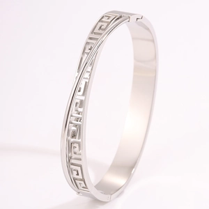 Macro view of silver stainless steel bangle with geometric fretwork pattern and hinge