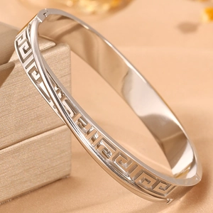 Macro detail of silver greek key hollow pattern on polished stainless steel hinge bangle
