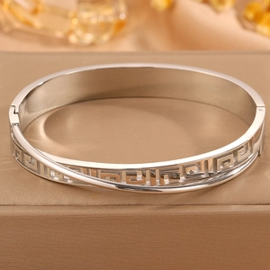 Close-up of golden stainless steel hinge bracelet featuring classic Greek Key pattern