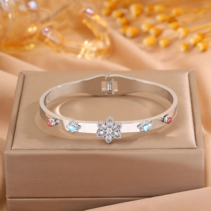 Macro detail of starburst steel bangle with blue and red zircon stones on silk cloth