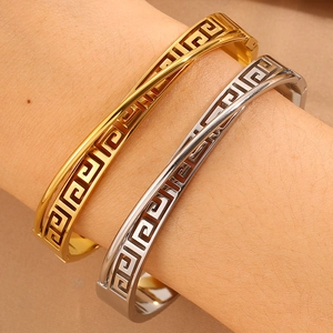 Golden and silver stainless steel open bangles featuring Greek key cutout patterns