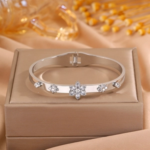 Detail of silver stainless steel starburst bangle with zircon inlays and floral accents
