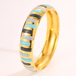 Macro shot of gold stainless steel bangle with blue and black enamel stripe details