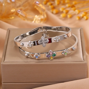 Detail showing two polished silver clover bangles with colorful zircon stones on display
