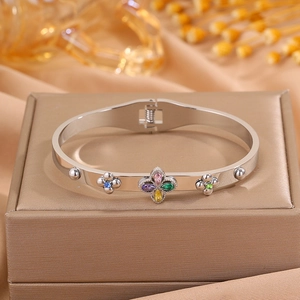 Detailed macro view of silver clover bangle with multi-color zircon stones on silk fabric