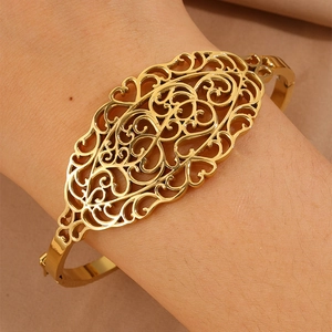 Dettaglio del bracciale rigido in acciaio al titanio dorato con motivi floreali traforati