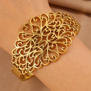 Dettaglio del bracciale dorato traforato con motivi a cuore e filigrana vintage sul polso
