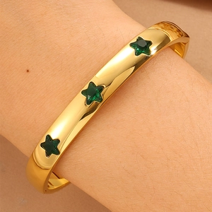 Detailansicht eines breiten goldenen Armbands mit drei eingelegten grünen Zirkonia-Sternen