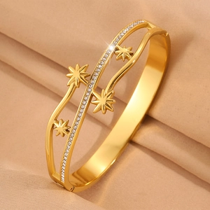 Détail de bracelet jonc plaqué or avec des étoiles à huit branches et des zircons