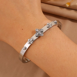 Elegant silver stainless steel open bangle featuring zircon clover flowers on female wrist