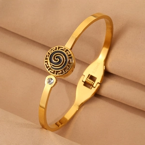 Macro shot of gold stainless steel bangle with black enamel Greek key pattern and crystal