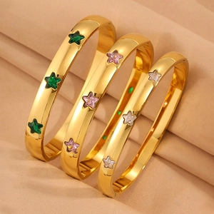 Drei goldene Edelstahl-Armbänder mit Sternkristallen in Grün, Lila und Weiß auf Seide