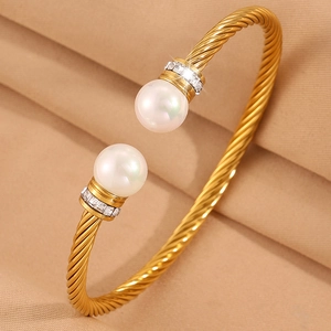 Vue détaillée du bracelet doré torsadé avec perles blanches et accents de strass brillants