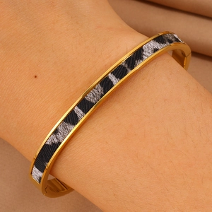 Makro-Detail des goldenen Edelstahl-Armreifs mit Leopardenmuster und Klappverschluss