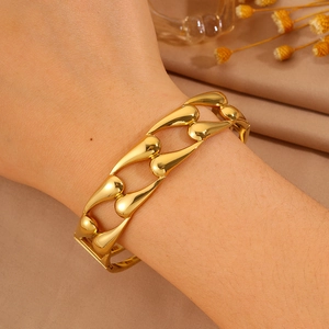 Close-up of a wide hollow teardrop gold titanium steel bracelet on a female wrist