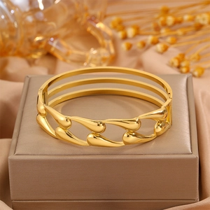 Golden stainless steel triple-layered hollow water drop bangle shown on a jewelry box