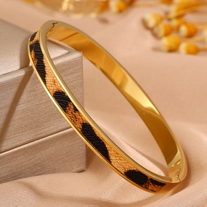 Luxuriöser goldener Edelstahl Armreif mit Leopardenmuster auf champagnerfarbenem Satin