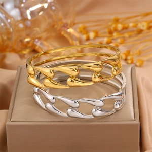 Gold and silver teardrop hollow titanium steel bangles on a jewelry display box