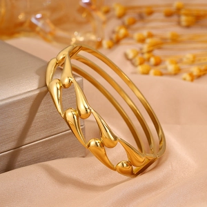 Golden hollow water drop titanium steel wide cuff bracelet on luxury silk background