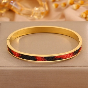 Detailansicht eines Gold-Edelstahlarmbands mit Leopardenmuster-Inlay auf einer Geschenkbox
