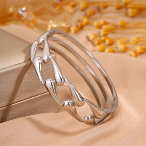 Macro view of wide hollow water drop bangle featuring a polished silver metallic finish