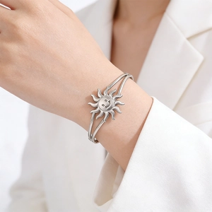 Detail of silver sun smile pendant on dual-line stainless steel open cuff bracelet
