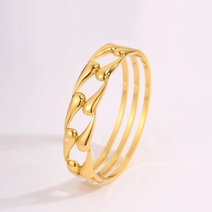 Detailed macro view of golden cutout teardrop bracelet with triple-ring band design