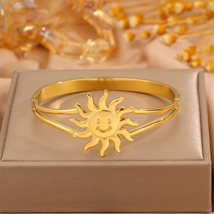 Detail shot of a sun smiley face gold stainless steel bangle on a luxury jewelry box
