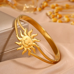 Detailed view of gold smiley face sun bracelet on jewelry box with silk fabric and flowers