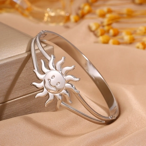 Detailed close-up of a silver smiling sun stainless steel cuff bracelet on silk