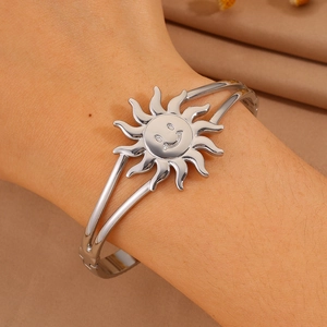 Detail showing a silver smiley face sun charm on an adjustable open bangle bracelet