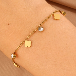 Close-up of golden titanium steel charm bracelet with clover and zircon on a wrist